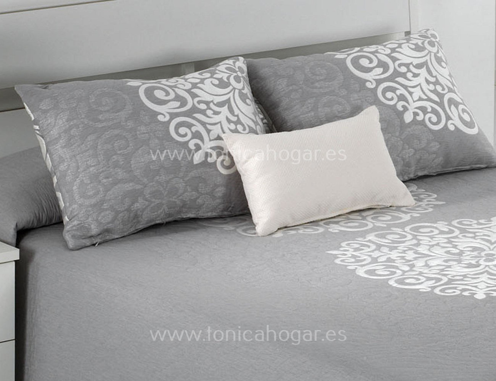 Cojines estampados sobre cama en tonos grises